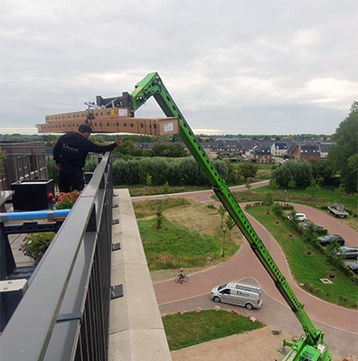 Professionele verreiker van Rutten Hoogteservice voor montage terrasoverkapping op 5e verdieping appartement