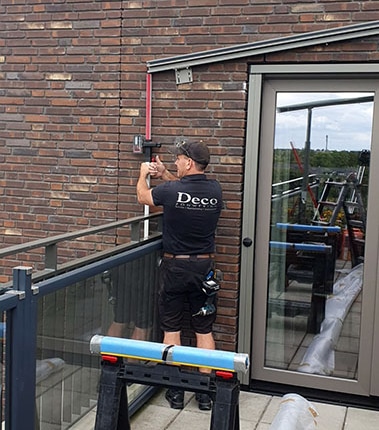 Deco Zonwering monteur tijdens installatie Plaza Viva terrasoverkapping op 5e verdieping penthouse