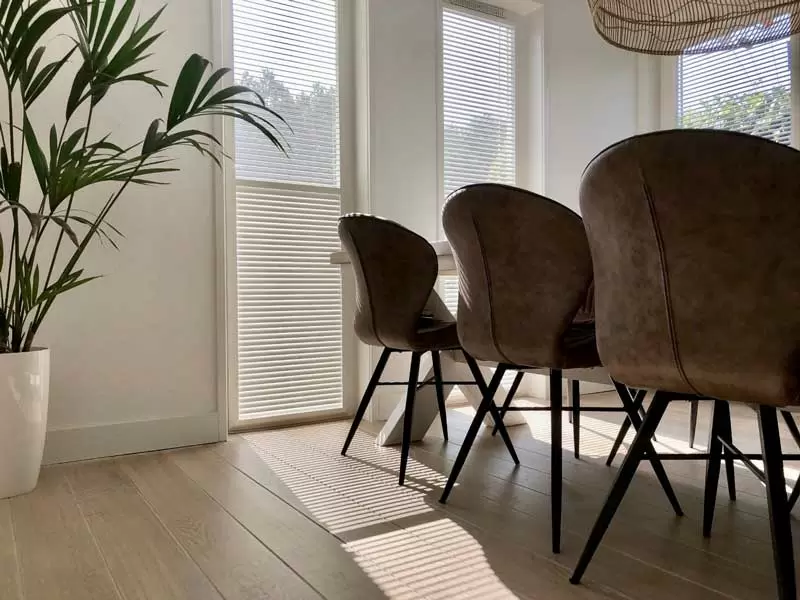 Lichte eetkamer met KeJe raamdecoratie en zonwering, verkrijgbaar bij Deco Zonwering.