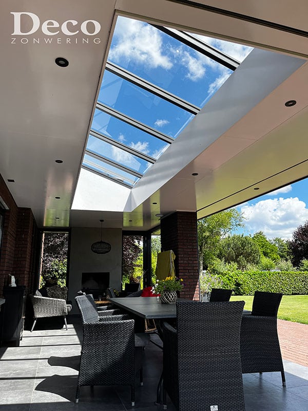 Lichtstraat zonder zonwering - volle zon komt door het glas Moderne overkapping met volledig open glazen lichtstraat laat heldere zon door naar terras met eettafel in Nistelrode