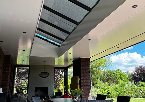 Volledig gesloten lichtstraat zonwering met grijs doek zorgt voor aangename schaduw onder overkapping