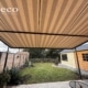 Weinor Plaza Viva doekoverkapping in antraciet met gestreept beige-bruin doek, gemonteerd aan woning in Nistelrode.