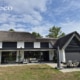 Achtergevel van een vrijstaande woning in Heesch met donkere solar screens, rieten dak en terrasoverkapping.